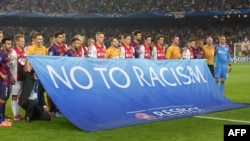 FILE - Barcelona and Ajax's players pose with a baner against racism before the UEFA Champions League football match FC Barcelona vs Ajax Amsterdam at the Camp Nou stadium in Barcelona on Oct. 21, 2014. 