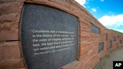 In this view through a fisheye lens, a plaque with a quote from President Bill Clinton is displayed on the wall of healing at the Columbine Memorial, April 17, 2024, in Littleton, Colorado. 