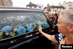 A hearse carrying the coffin of late Irish singer Sinead O'Connor passes by during her funeral procession as fans line the street to say their last goodbye to her, in Bray, Ireland, Aug. 8, 2023.