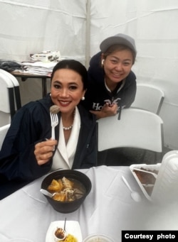 Istri Dutabesar Indonesia untuk AS, Ayu Heni Roeslani sedang menikmati Bakso Super Philly bersama Yen Yen di belakangnya (foto: courtesy).