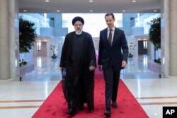 Presiden Suriah Bashar Assad (kanan), berjalan bersama Presiden Iran Ebrahim Raisi di istana kepresidenan di Damaskus, Suriah, Rabu, 3 Mei 2023. (Kepresidenan Suriah via Facebook via AP )