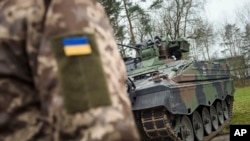 FILE - A Ukrainian soldier in front of a Marder infantry fighting vehicle in Munster, Germany, Feb. 20, 2023. Germany is giving Ukraine 2.7 billion euros more in military aid.