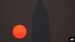The sun rises behind the Washington Monument and a thick layer of smoke, June 8, 2023, in Washington.