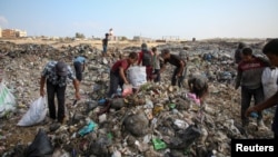 Warga Palestina mengais barang-barang yang dapat digunakan di tempat pembuangan sampah, di tengah konflik Israel-Hamas, di Khan Younis di selatan Jalur Gaza, 15 Juli 2024. (Foto: REUTERS/Hatem Khaled)