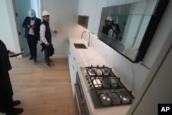 FILE - Joey Chilelli, right, managing director of real estate firm Vanbarton Group, and the company's senior project manager Malek Hajar, show the kitchen in a model apartment inside a high rise at 160 Water Street in New York on Tuesday, April 11, 2023. (AP Photo/Bebeto Matthews)