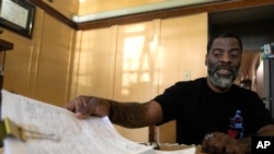 Chicago School Board candidate, rapper Che 'Rhymefest' Smith, looks over signature petitions for his candidacy during an interview with The Associated Press at his home in the Chatham neighborhood of Chicago, May 21, 2024. 