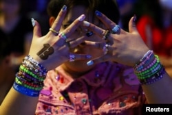 Luke, 22, dari Shandong, China, memamerkan gelang-gelangnya di hadapan penggemar Taylor Swift, atau Swifties, saat bernyanyi menjelang konser Swift's Eras Tour, di Bandara Jewel Changi di Singapura. (Foto: Reuters)