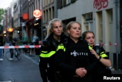 FILE - Police officers look on as they stand guard to secure the area where Dutch celebrity crime reporter Peter R. de Vries was reportedly shot and seriously injured, in Amsterdam, Netherlands, July 6, 2021.