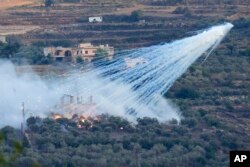 A shell from Israeli artillery explodes over a house in al-Bustan, a Lebanese border village with Israel, south Lebanon, Oct. 15, 2023.