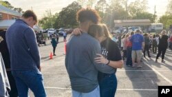 Dua orang remaja tampak saling berpelukan dalam acara doa bersama yang digelar untuk para korban insiden penembakan di Dadeville, Alabama, pada 16 April 2023. (Foto: AP/Jeff Amy)