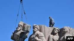 Workers take down the Soviet-era monument symbolizing the Pereiaslav Agreement signed in 1645, a pledge of allegiance by Ukranian Cossacks to the Tsar of Russia, in Kyiv.