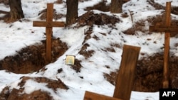 This photo taken on Feb. 25, 2023, shows an Orthodox icon near empty graves after the exhumation of bodies from mass graves dug during the Russian occupation of the town of Izyum, in Ukraine's Kharkiv region. 