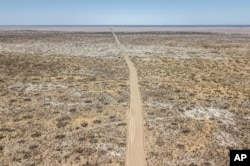 FILE - A dirt road stretches through the desert that used to be the bed of the Aral Sea, on the outskirts of Muynak, Uzbekistan, June 27, 2023. Some environmentalists warn that the Aral offers a cautionary tale for the Caspian Sea.