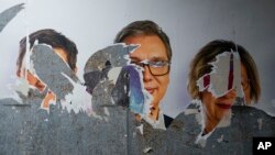 A vandalized campaign billboard shows Serbian President Aleksandar Vucic, center, with associates after a local election in Belgrade, Serbia, June 2, 2024. 