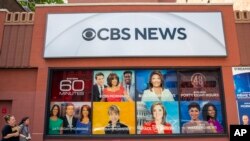 FILE - People pass the CBS Broadcast Center on 57th Street in New York, April 20, 2023. CBS News has asked all its local stations to become proficient in solutions journalism.