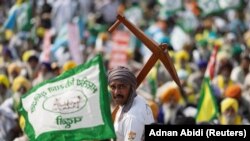 Seorang petani memegang bajak tiruan di tengah pertemuan besar dewan desa sebagai bagian dari protes petani yang menuntut jaminan harga yang lebih tinggi untuk hasil panen mereka, New Delhi, India, 14 Maret 2024. (Foto: REUTERS/Adnan Abidi)