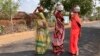 Tiga orang perempuan berjalan sambil membawa kendi berisi air minum pada suatu sore musim panas yang terik di Lalitpur, negara bagian Uttar Pradesh, India, Sabtu, 17 Juni 2023. (AP/Rajesh Kumar Singh)