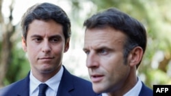 FILE - French Education and Youth Minister Gabriel Attal (L) looks at France's President Emmanuel Macron addressing an audience at a vocational school in Orange, Southeastern France, Sept. 1, 2023.