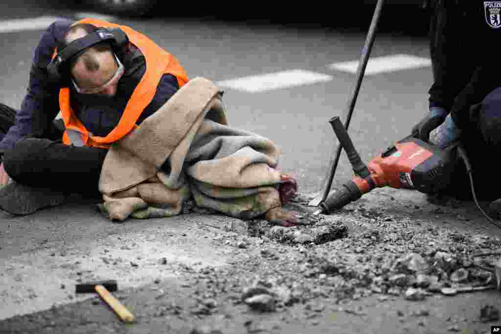 Police remove the asphalt from the hand of a climate activist who glued his hand to the road, during a protest against the climate policy of the German government in Berlin, Germany.
