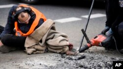 Police remove the asphalt from the hand of an climate activist who glued his hand to the road, during a protest against the climate policy of the German government in Berlin, Germany.