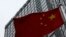 FILE - A building housing the PricewaterhouseCoopers (PWC) branch office stands behind a Chinese national flag in Beijing, Jan. 24, 2014. 