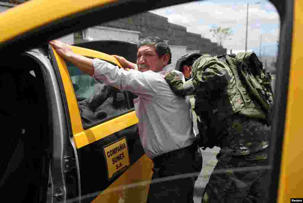 A soldier inspects a car and his driver at a military checkpoint prior to Sunday's presidential election, in Quito, Ecuador, Aug. 14, 2023.