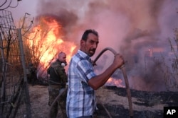 Volunteers try to extinguish the fire in northern Athens as hundreds of firefighters tackle a major wildfire raging out of control on fringes of the Greek capital, Aug. 12, 2024.