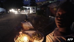 FILE - Sierra Leonean street vendor lights her stand with a candle in Freetown, where residents are experiencing one of the worst energy crises since the end of the 10-year civil war in 2001.