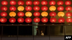 People walk behind lanterns among the department stores at the Xinyi district in Taipei on Jan. 16, 2024.