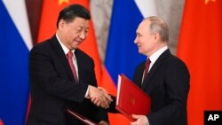 FILE - Russian President Vladimir Putin and Chinese President Xi Jinping shake hands as they exchange documents during a signing ceremony following their talks at the Grand Kremlin Palace in Moscow, March 21, 2023.