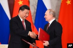Russian President Vladimir Putin, right, and Chinese President Xi Jinping shake hands as they exchange documents during a signing ceremony following their talks at the Grand Kremlin Palace, in Moscow, Russia, March 21, 2023.