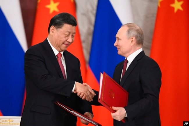 FILE - Russian President Vladimir Putin, right, and Chinese President Xi Jinping shake hands as they exchange documents during a signing ceremony following their talks at the Grand Kremlin Palace, in Moscow, Russia, March 21, 2023.
