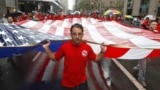 FILE - Iron worker Robert Farula marches up Fifth Ave. carrying an American flag during the Labor Day parade on Sept. 8, 2012, in New York. (AP Photo/Mary Altaffer, File)