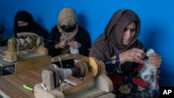 Women weave wool for traditional Afghan carpets at a factory in Kabul, Afghanistan, March 6, 2023.