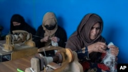 Women weave wool for traditional Afghan carpets at a factory in Kabul, Afghanistan, March 6, 2023. 