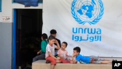 FILE - Palestinian children who fled with their parents from their houses in the Palestinian refugee camp of Ein el-Hilweh, gather in the backyard of an UNRWA school, in Sidon, Lebanon, Sept. 12, 2023.