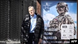 A man walks in front of a poster promoting contract army service and reading "Our job, defending the homeland" in Moscow on April 12, 2023.