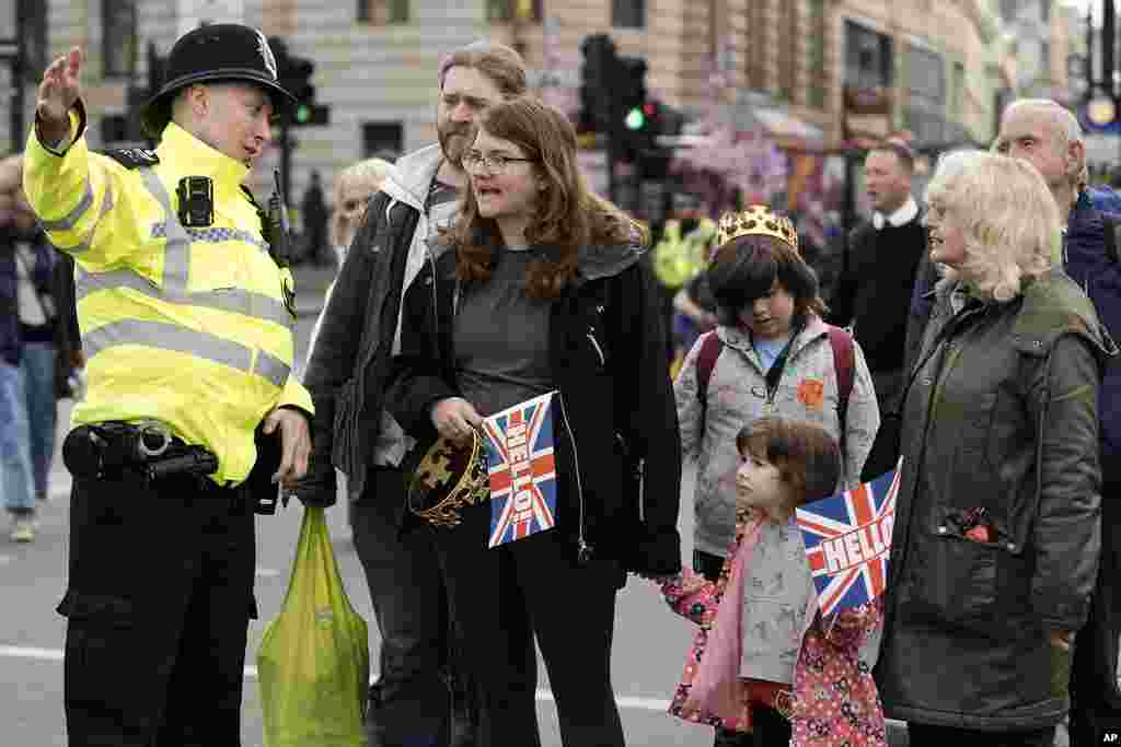 A policeman directs a family to the public viewing areas to watch Britain's King Charles III's procession to Westminster Abbey for his coronation in London, May 6, 2023.