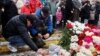 Beberapa pria menyalakan lilin sebagai tanda penghormatan untuk mengenang para korban serangan penembakan di konser di Balai Kota Crocus di Wilayah Moskow, Rusia, 23 Maret 2024. (Foto: REUTERS/Yulia Morozova)