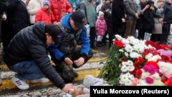 Beberapa pria menyalakan lilin sebagai tanda penghormatan untuk mengenang para korban serangan penembakan di konser di Balai Kota Crocus di Wilayah Moskow, Rusia, 23 Maret 2024. (Foto: REUTERS/Yulia Morozova)