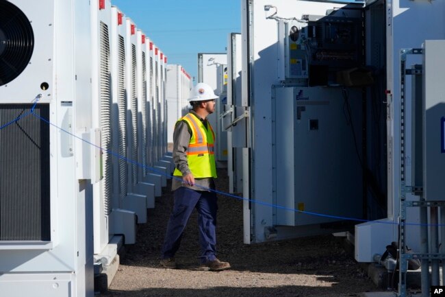 A worker checks battery storage at Orsted's Eleven Mile Solar Center on Feb. 29, 2024, in Coolidge, Ariz. Batteries allow renewables to replace fossil fuels while keeping a steady flow of power when sources like wind and solar are not producing. (AP Photo/Ross D. Franklin)