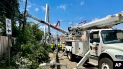 Crews replace utility poles felled last week by deadly storms, in Houston, Texas, May 19, 2024.