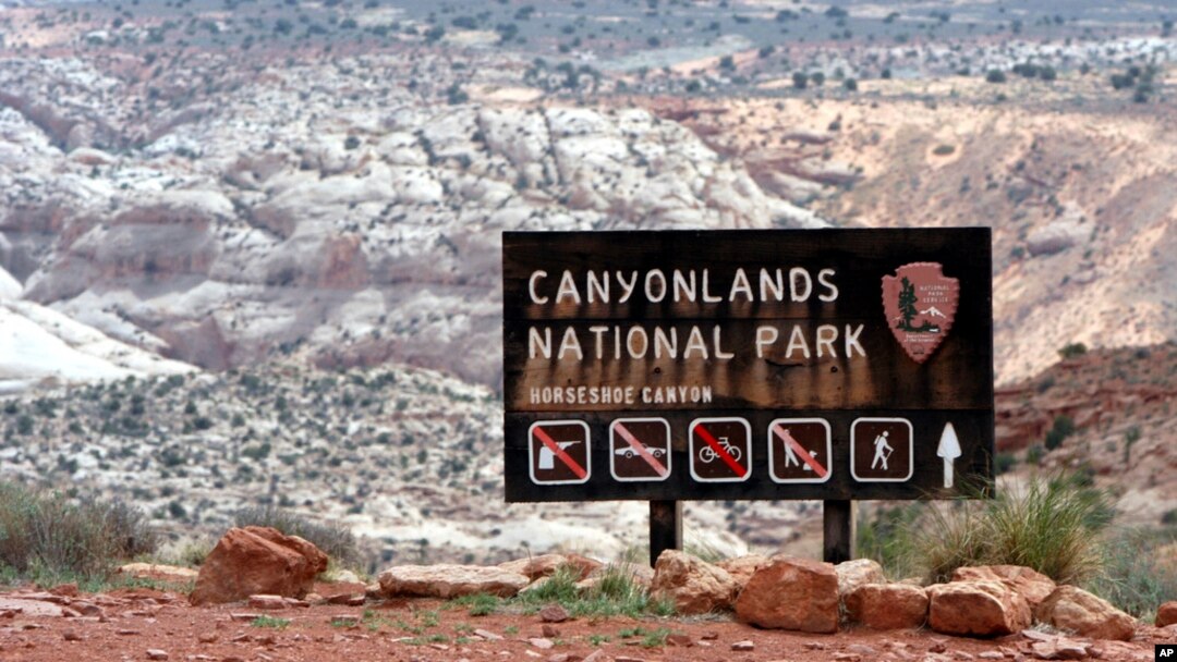 FILE - A sign for Canyonlands National Park is seen in Moab, Utah, May 6, 2003. Three hikers died over the weekend in suspected heat-related incidents at parks in Utah.