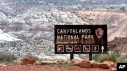 FILE - A sign for Canyonlands National Park is seen in Moab, Utah, May 6, 2003. Three hikers died over the weekend in suspected heat-related incidents at parks in Utah.