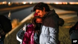 FILE - A couple from Cuba wait to be processed to seek asylum after crossing the border into the United States, near Yuma, Arizona, Jan. 6, 2023.