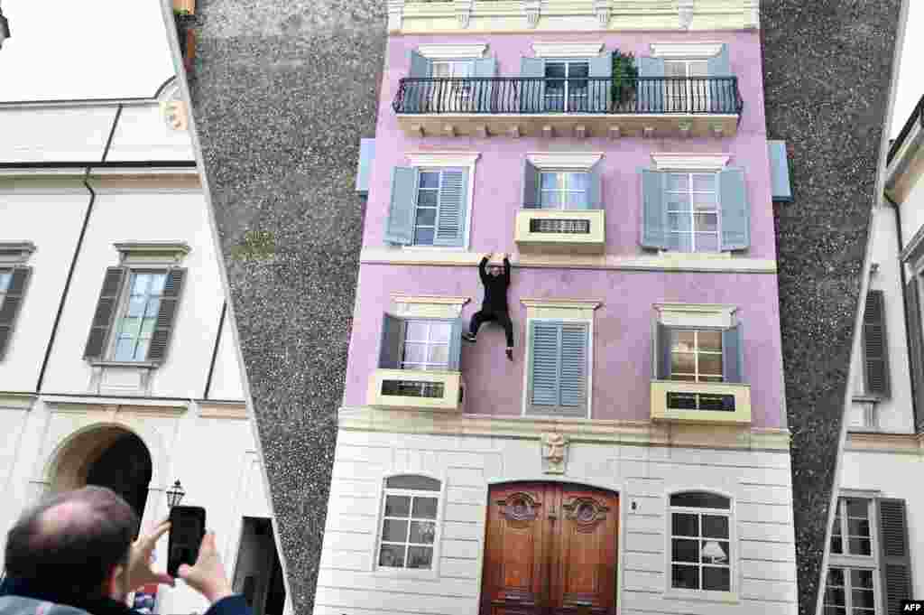 A visitor poses for pictures on "Palazzo" (Building), an installation by Argentinian artist Leandro Erlich, during a media day of his exhibition "Over the threshold" at the Palazzo Reale in Milan.