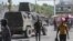 FILE - People walk past an armored police vehicle patrolling the streets in Port-au-Prince, July 15, 2024. 