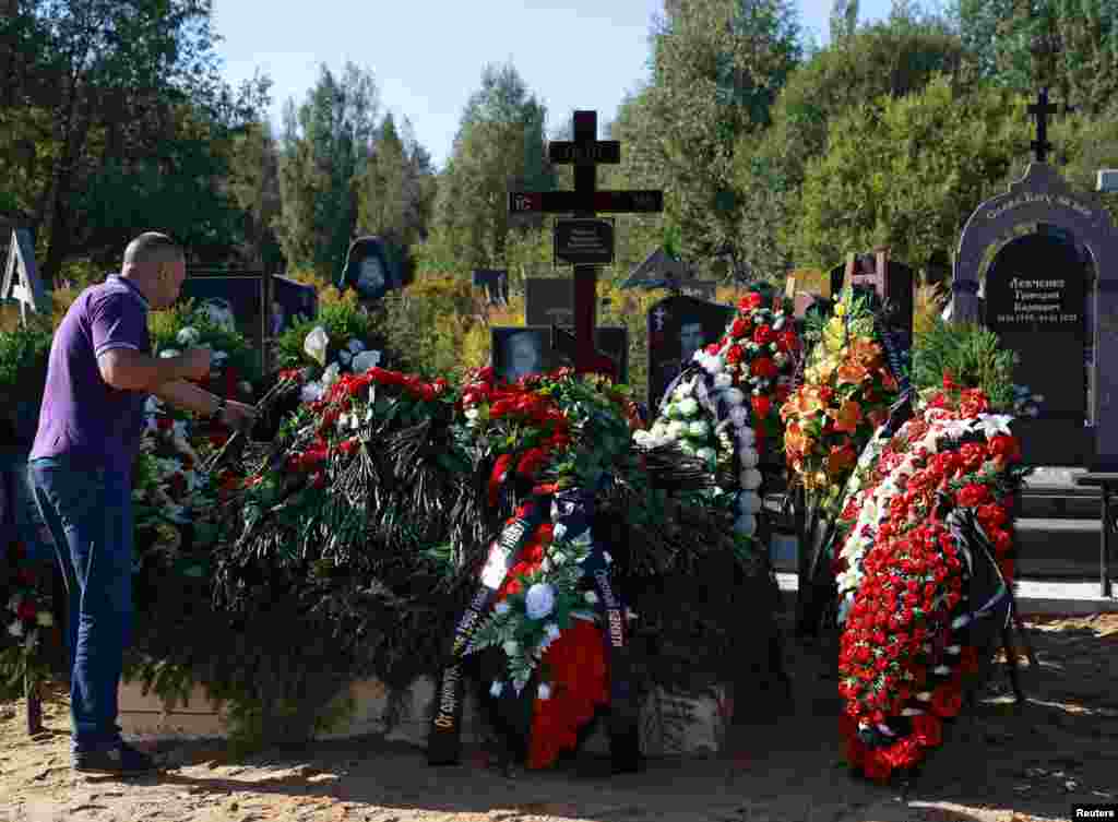 A man places flowers at the grave of Valery Chekalov, logistics chief of the Wagner private mercenary group, after his funeral at the Severnoye cemetery in St. Petersburg, Russia.