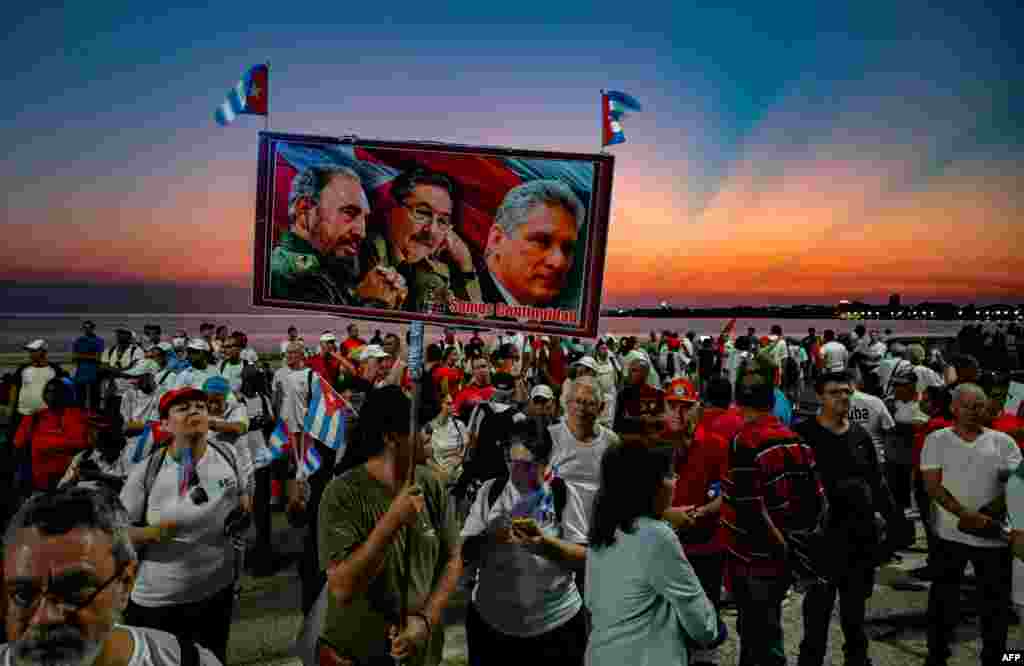 A demonstrator carries a poster with images of late Cuban president Fidel Castro, Cuban former president Raul Castro, and Cuban president Miguel Daz Canel during the commemoration of May Day, to mark the international day of the workers in Havana.