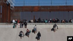 Migrantes se acercan al muro fronterizo en Ciudad Juárez, México, el 21 de diciembre de 2022, al otro lado de la frontera desde El Paso, Texas, EEUU.